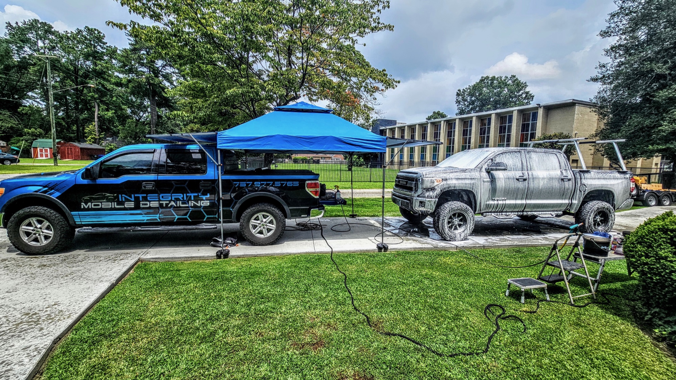 Integrity Mobile Detailing truck and canopy set up beside a customer pickup
